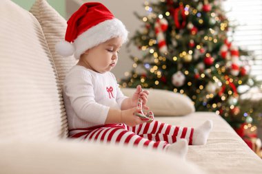 Noel Baba şapkalı şirin bir bebek. Kanepede şeker kamışı var. Mesaj için yer var. Noel sezonu