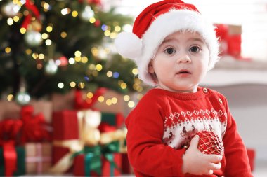 Evde yerde Noel Baba şapkası ve süslemeleri olan şirin bir bebek, mesaj atmak için yer var. Noel sezonu