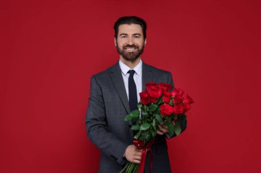 Sevgililer Günü. Kırmızı arka planda gül buketi olan yakışıklı adam.