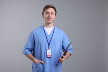 Gri arkaplanda panosu olan tıbbi asistanın portresi