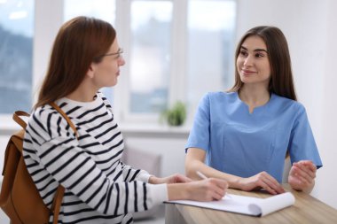 Klinikteki resepsiyonda hastaya yardım eden tıbbi asistan