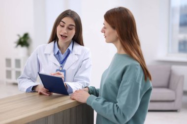 Klinikteki resepsiyonda hastaya yardım eden tıbbi asistan