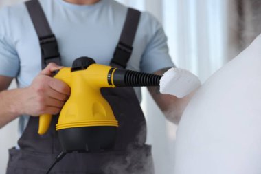 Haşere kontrol görevlisi yastığı temizliyor, kapalı alanda temizliyor, yakın plan.