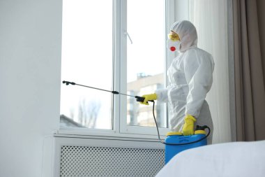 Koruyucu giysiler içinde böcek ilacı sıkan haşere kontrol görevlisi.