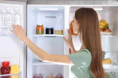 Genç kadının yanına açık buzdolabı mutfak