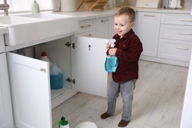 Evde çocuk güvenliği. Küçük çocuk mutfakta temizlik ürünleriyle oynuyor.