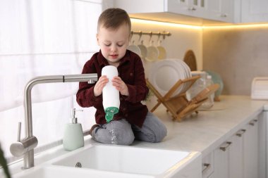 Evde çocuk güvenliği. Küçük çocuk mutfakta lavabonun yanında tozla oynuyor, mesaj için yer var.
