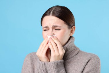 Açık mavi arka planda burnu akan bir kadın. Soğuk Semptom