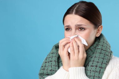 Açık mavi arka planda burnu akan bir kadın, yakın plan ve mesaj için yeri var. Soğuk Semptom