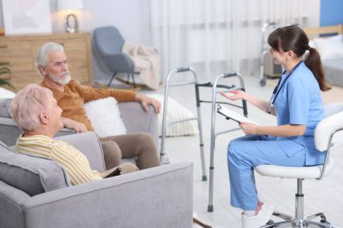 Bakım görevlisi yaşlı kadın ve erkeğe huzurevinde iyi olup olmadıklarını soruyor.