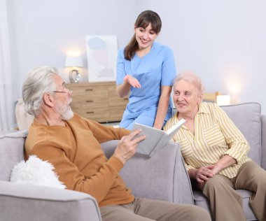 Yaşlı adam, kadın ve bakıcı huzurevinde kitabı tartışıyorlar.