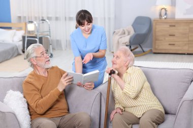 Yaşlı adam, kadın ve bakıcı huzurevinde kitabı tartışıyorlar.