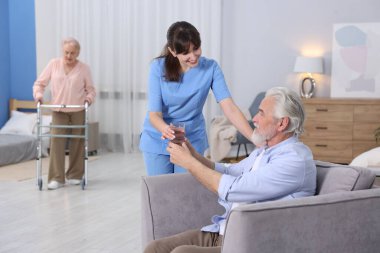 Bakım işçisi huzurevindeki yaşlı adama bir bardak su veriyor.