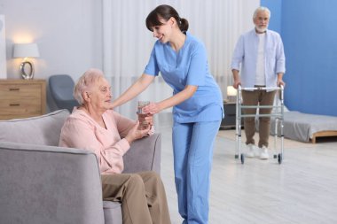 Huzurevindeki yaşlı kadına bir bardak su veren bakıcı.