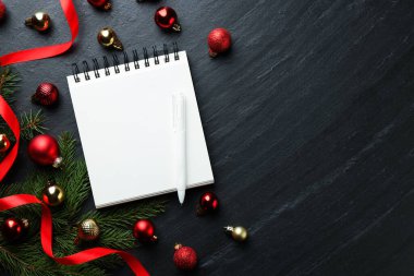 Yeni yıl hedefleri. Planlayıcı, kalem ve Noel dekoru siyah masada, düz yatıyordu. Metin için boşluk
