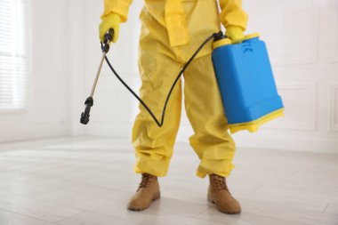 Koruyucu kıyafetli haşereci böcek ilacı sıkıyor, yakın plan.