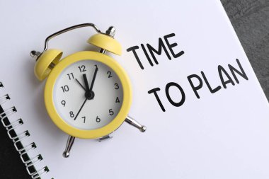 Plan yapma zamanı. Alarm saati ve defter masanın üstünde, üst görünümde.