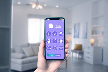 Akıllı ev sistemi. Oda özelliklerini kontrol etmek için cep telefonundaki uygulamayı kullanan adam, yakın plan