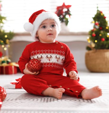 Evde yerde Noel Baba şapkası ve süslemeleri olan şirin bir bebek, mesaj atmak için yer var. Noel sezonu