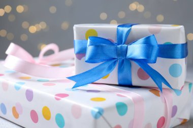 Gri arka planda güzel paketlenmiş hediyeler, bulanık ışıklar, yakın plan. Bokeh etkisi