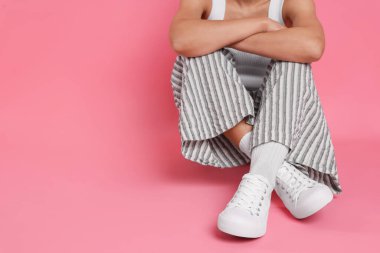 Pembe arka planda şık beyaz ayakkabılar giyen bir kadın, yakın plan. Metin için boşluk