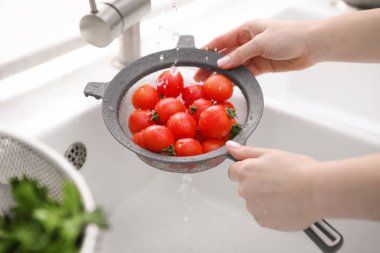 Lavaboda vişneli domatesleri elek ile yıkayan kadın, yakın plan.