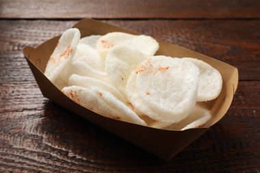 Lezzetli pirinç cipsleri paket kutusunda, ahşap masada, yakın plan.