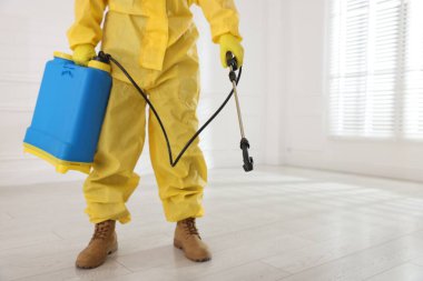 Koruyucu giysiler içinde böcek ilacı sıkan haşere kontrol görevlisi, yakın plan. Metin için boşluk