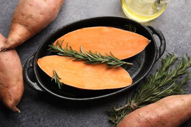 Çiğ patates, biberiye ve yağ siyah masada, düz yerde.