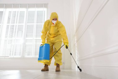 Koruyucu giysiler içinde böcek ilacı sıkan haşere kontrol görevlisi, düşük açılı.