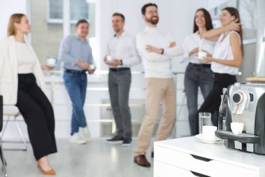 Mesai arasında sıcak içeceklerle iş arkadaşları kahve yapan elektrikli espresso makinesine odaklanır.