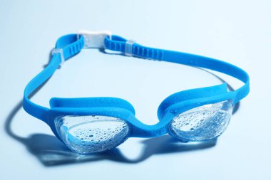 Açık mavi arka planda yüzme gözlükleri, yakın plan