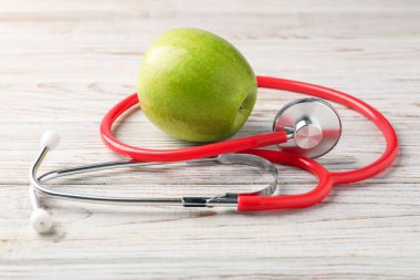 Olgun elma ve steteskop ahşap masada, yakın plan.