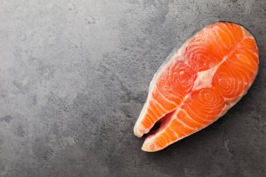 Piece of salmon fillet on gray textured table, top view. Space for text