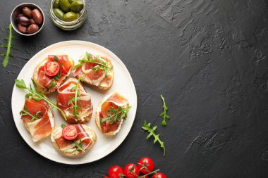 Krem peynirli nefis bruschettalar, prosciutto, domates ve roka koyu dokulu masa, düz yatak. Metin için boşluk