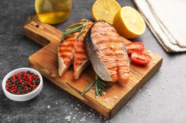 Lezzetli ızgara somon bifteği, domatesli ve biberiyeli, yakın plan.