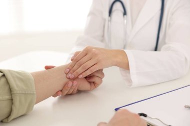 Doktor masadaki parmaklarıyla adamın nabzını kontrol ediyor.