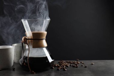 Cam kimya kahve makinesi, lezzetli kahve, fasulye ve fincanlar gri masada, yakın plan. Metin için boşluk