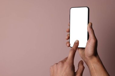 Dusty Rose arka planında boş ekranlı akıllı telefon tutan adam, yakın plan. Tasarım için model
