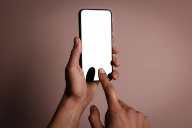 Dusty Rose arka planında boş ekranlı akıllı telefon tutan adam, yakın plan. Tasarım için model