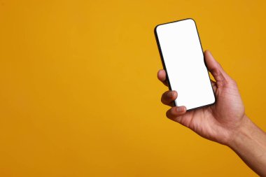 Turuncu arka planda boş ekranlı akıllı telefon tutan adam, yakın plan. Tasarım için model