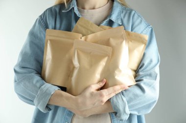 Açık gri arka planda stand-up kesesi olan kadın, yakın plan.