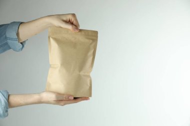 Açık gri arka planda stand-up kesesi olan kadın, yakın plan. Metin için boşluk