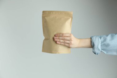 Açık gri arka planda stand-up kesesi olan kadın, yakın plan.