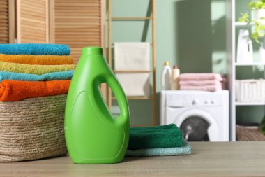 İçerideki ahşap masanın üzerinde havlu ve bir şişe deterjan olan çamaşır sepeti. Metin için boşluk