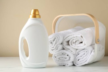 Çamaşır sepetinin içinde havlular ve bir şişe deterjan var.
