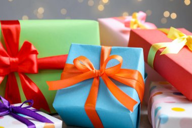 Gri arka planda güzel paketlenmiş hediyeler, bulanık ışıklar, yakın plan. Bokeh etkisi