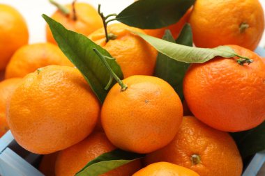 Taze mandalina ve yeşil yapraklar masada, yakın plan.