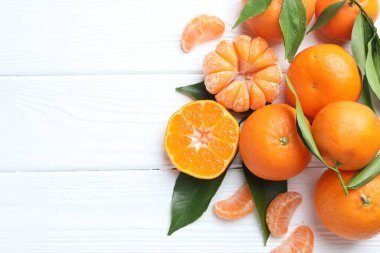 Taze mandalina ve yeşil yapraklar beyaz ahşap masada, düz yerde. Metin için boşluk