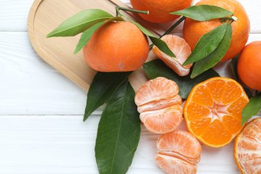 Taze mandalina ve yeşil yapraklar beyaz ahşap masada, düz yerde. Metin için boşluk